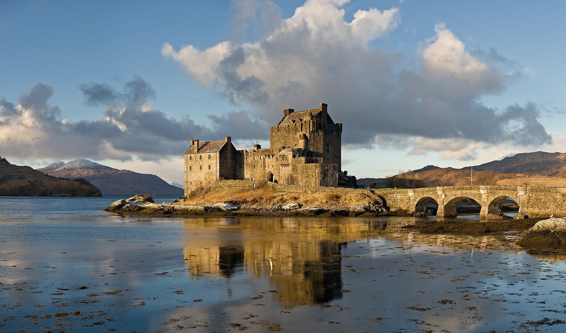 Eilean Donan Castle in Scotland with bridge and clear loch reflection