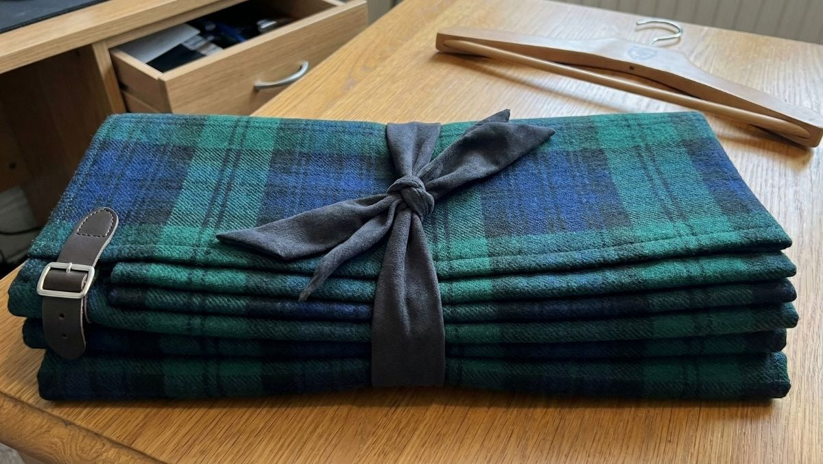 A neatly folded tartan kilt fastened with a cloth tie to maintain shape and protect the pleats.