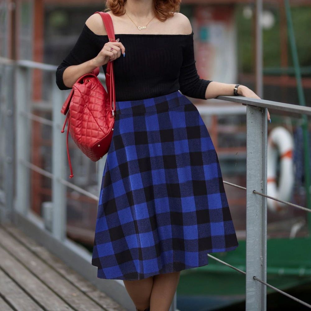 Woman wearing a blue plaid skirt with off-shoulder black top and red quilted handbag