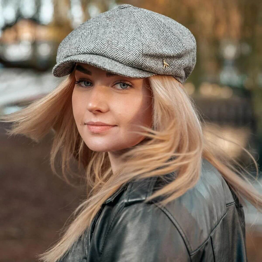 Woman wearing a grey herringbone English baker boy cap outdoors