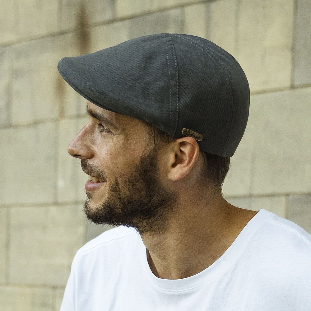 A man wearing a dark ivy cap, shown in side profile with a casual outfit.