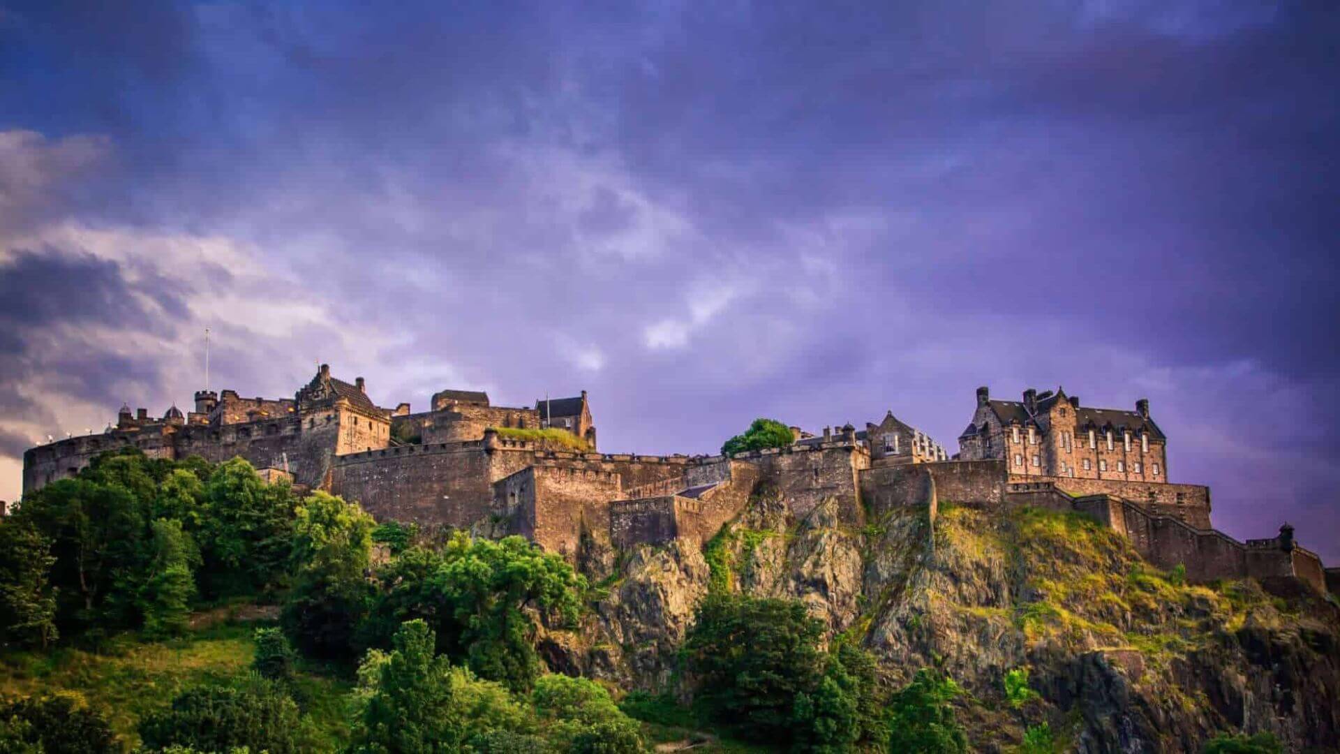 Edinburgh Castle perched on rocky cliffs under dramatic evening skies.
