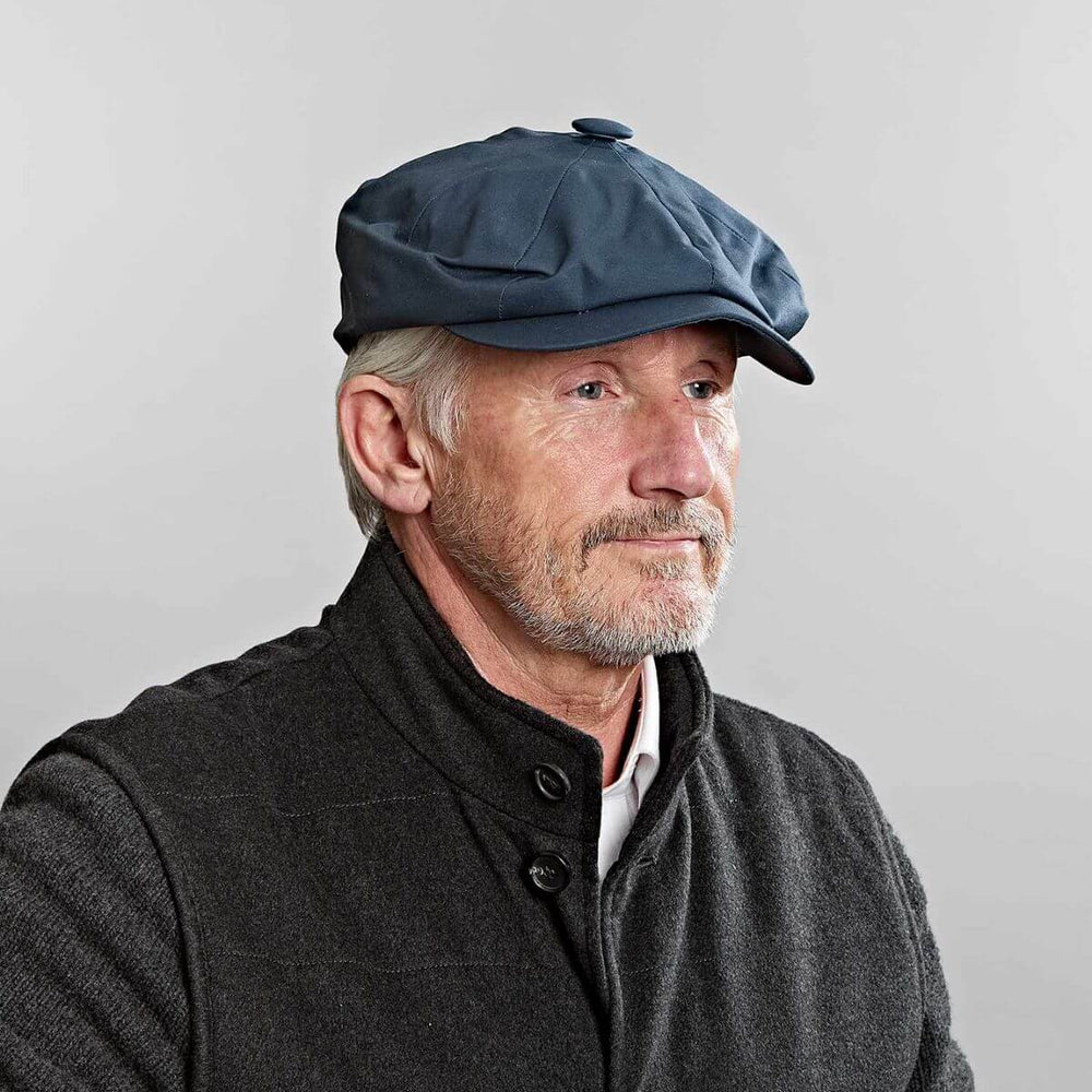 Man wearing a navy blue Gatsby cap with a classic eight-panel design