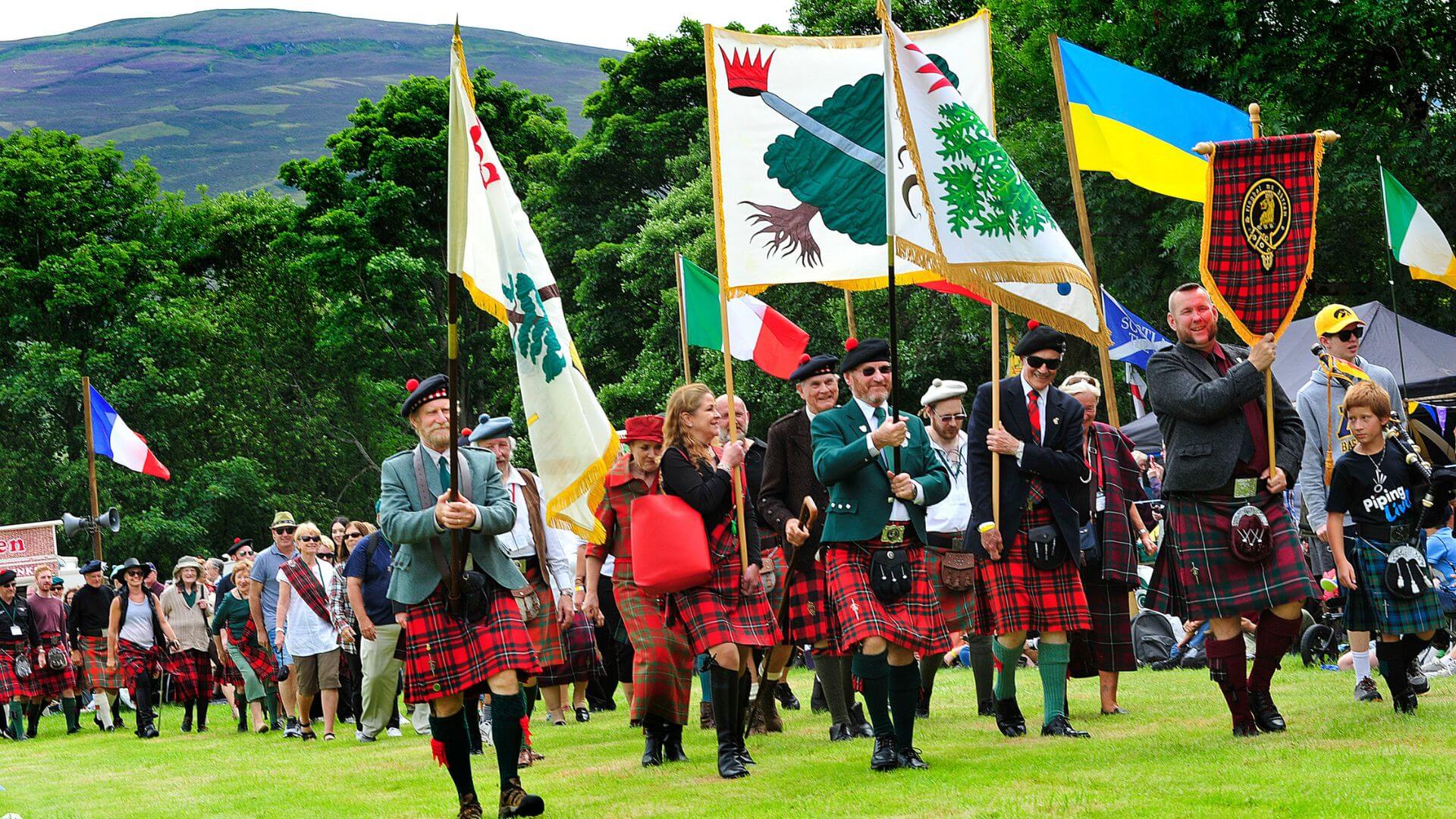 Clan MacGregor members in traditional Scottish kilts at Highland gathering.