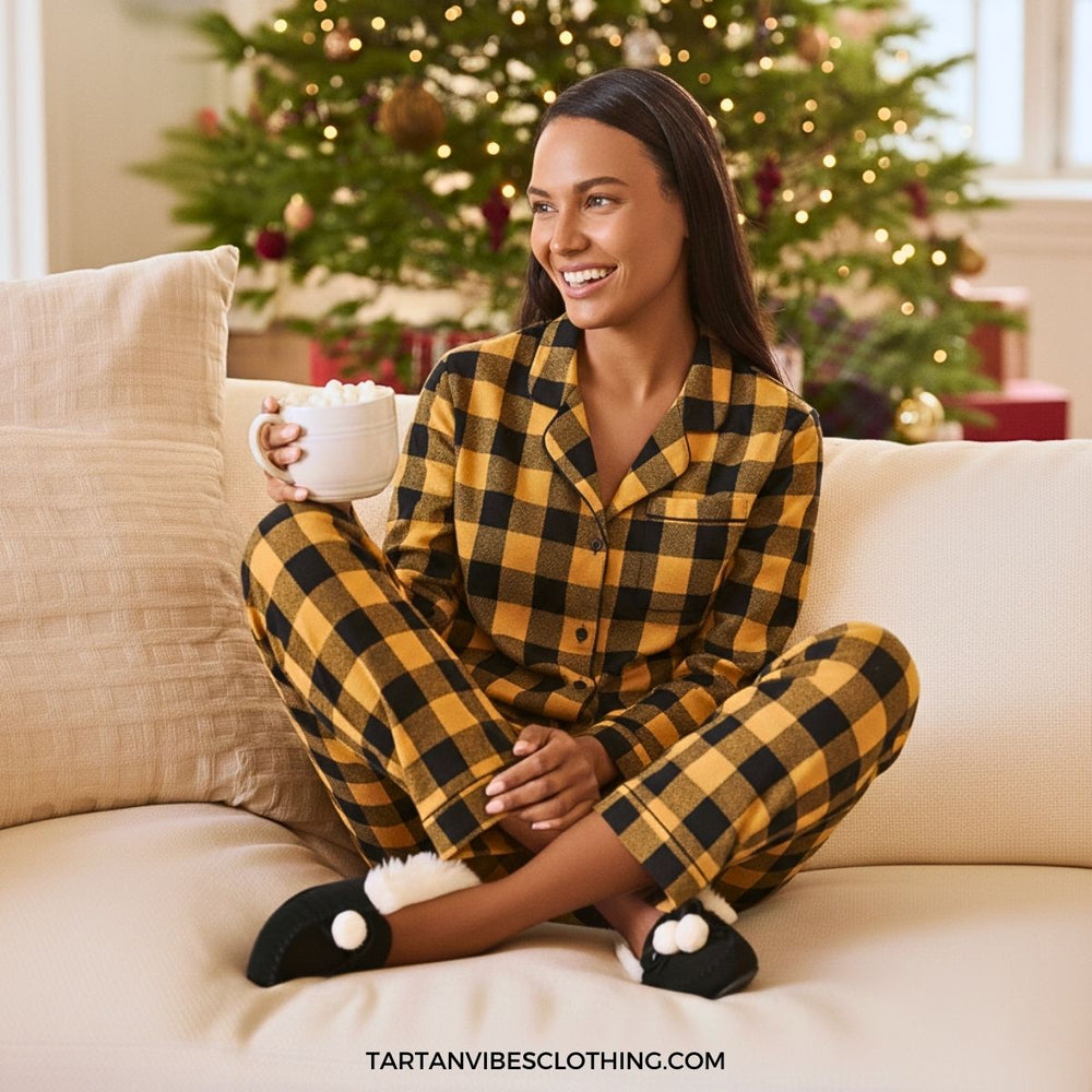 Person wearing cozy yellow plaid flannel pajamas while relaxing on a sofa with a warm drink during the holidays.