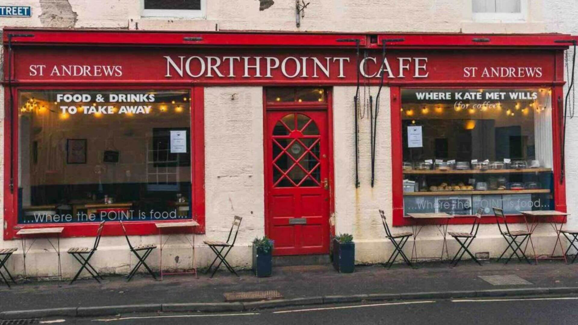 Front view of Northpoint Café in St Andrews, Scotland — a charming red-fronted café famous as the spot “Where Kate Met Wills,” featuring outdoor seating and cozy interior lighting.