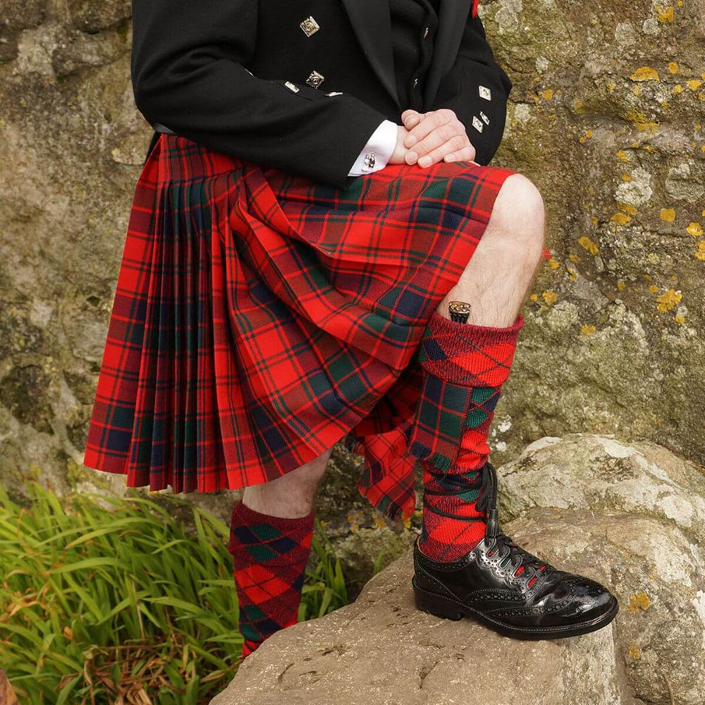 Traditional red tartan Scottish kilt with matching socks and black dress shoes.
