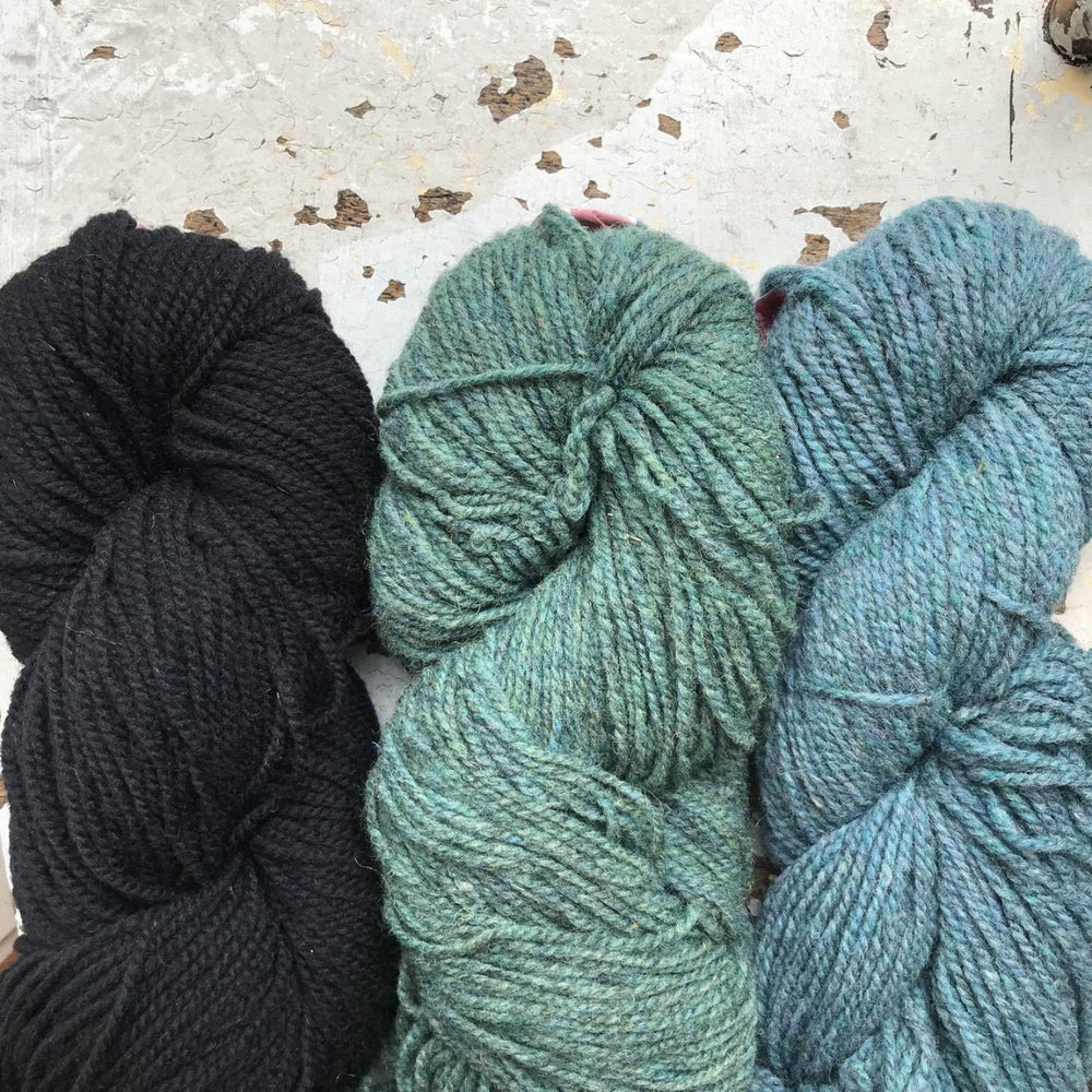 100 percent worsted wool yarn skeins in natural black green and blue shades