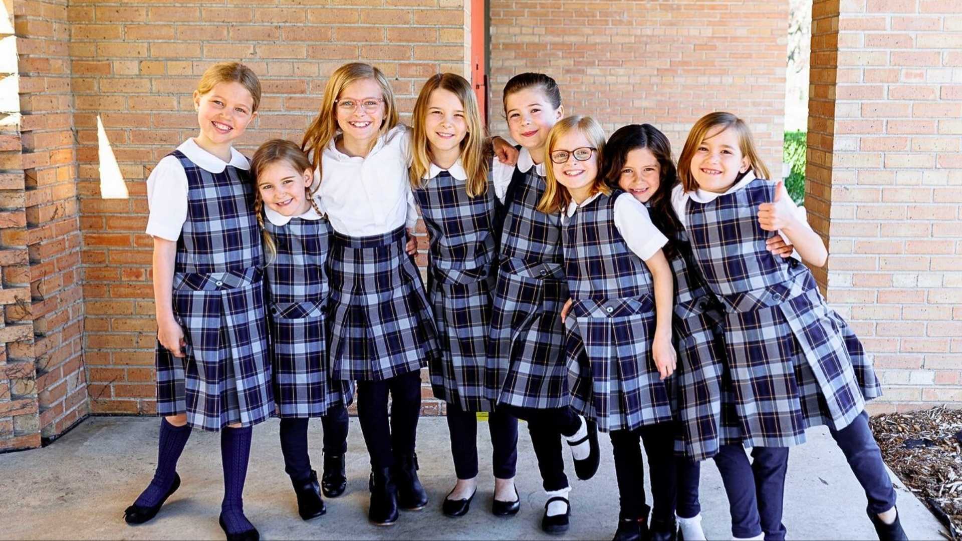 Young students in matching plaid jumpers and white shirts.